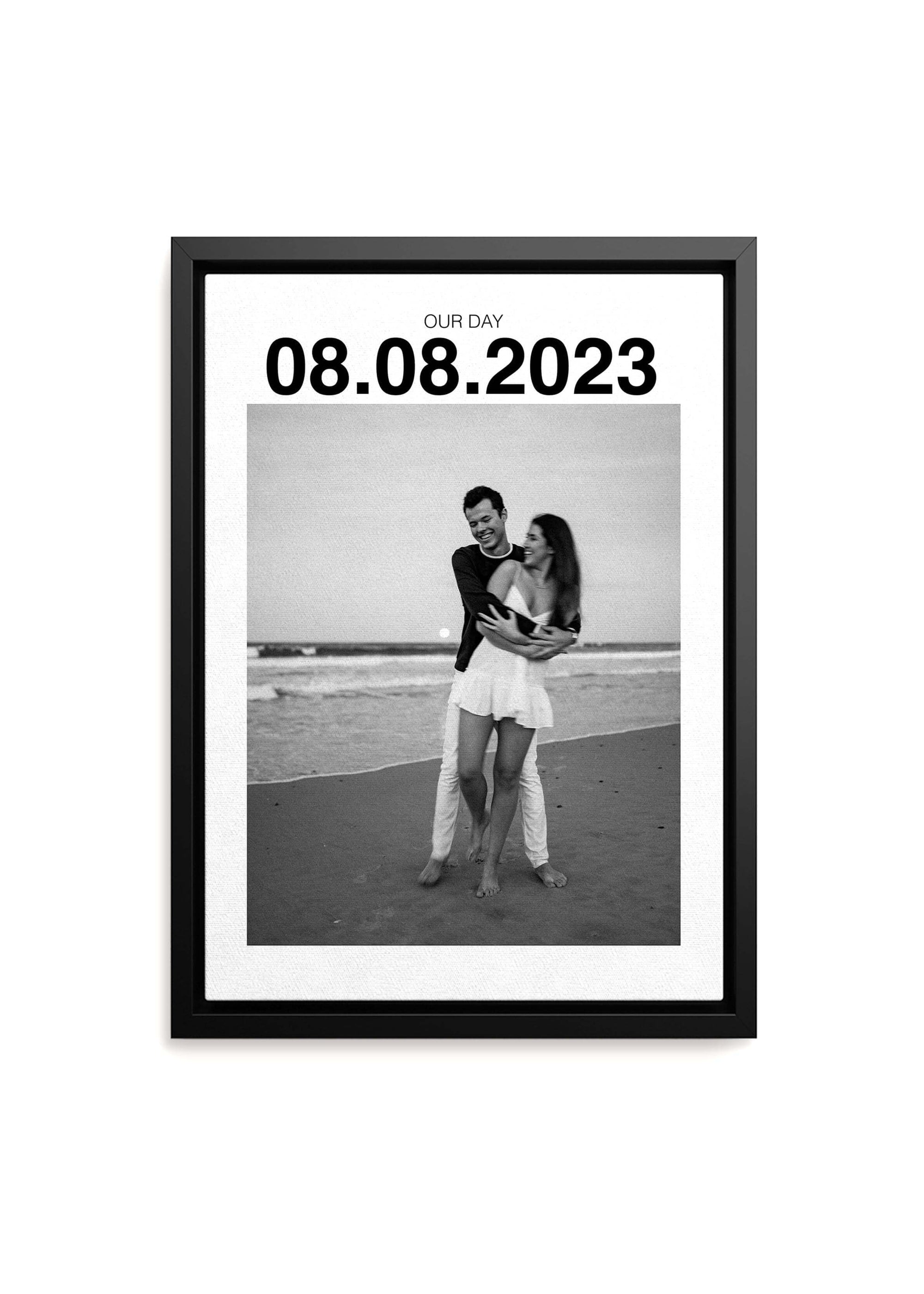 Personalized anniversary gift canvas with large custom date on black framed canvas and a couple on the beach smiling in black and white. Canvas is on a white background.