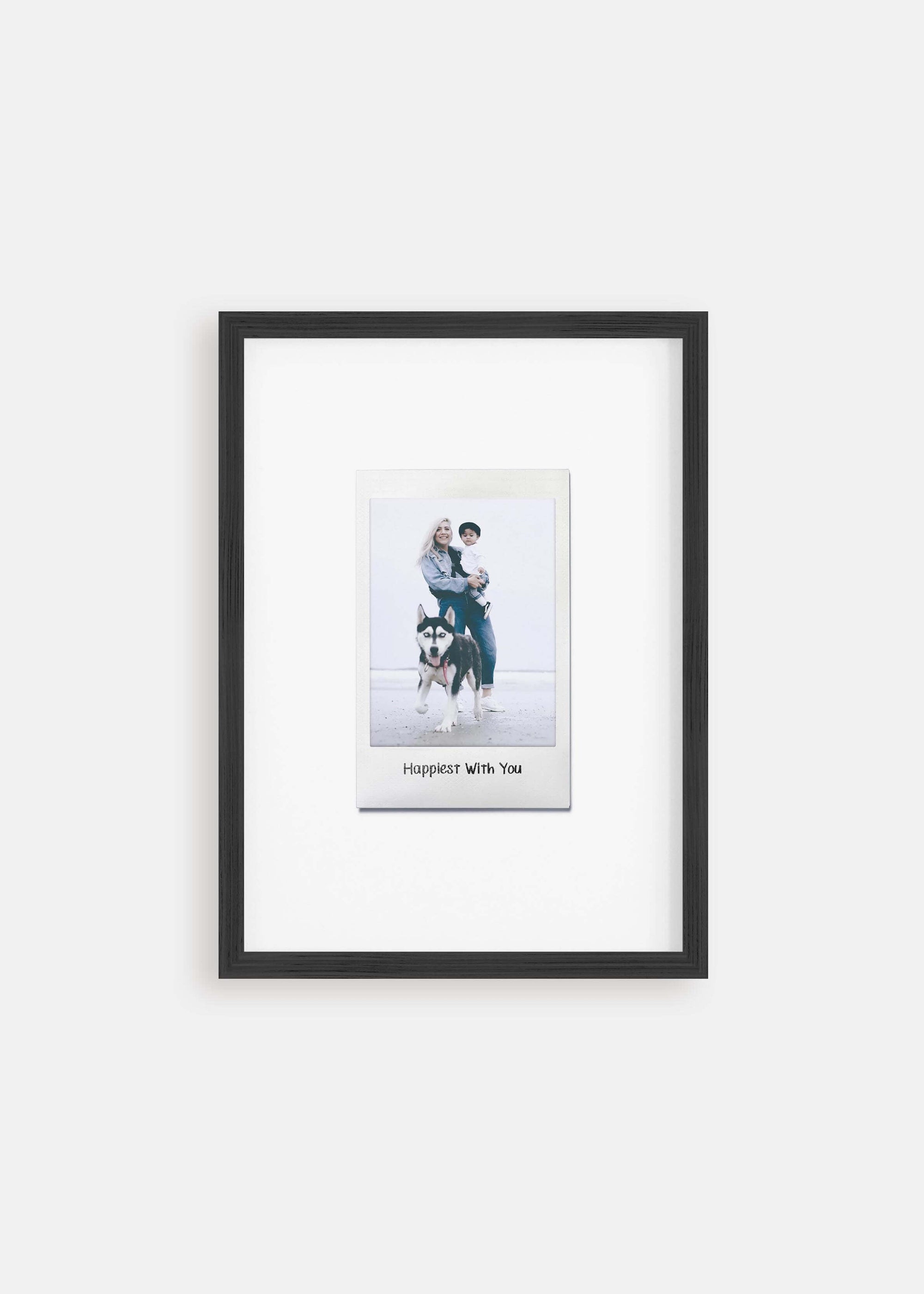 Personalized photo gift of a woman with her child and dog in a black frame in the style of a nostalgic instant film custom polaroid photo with frame on white background.