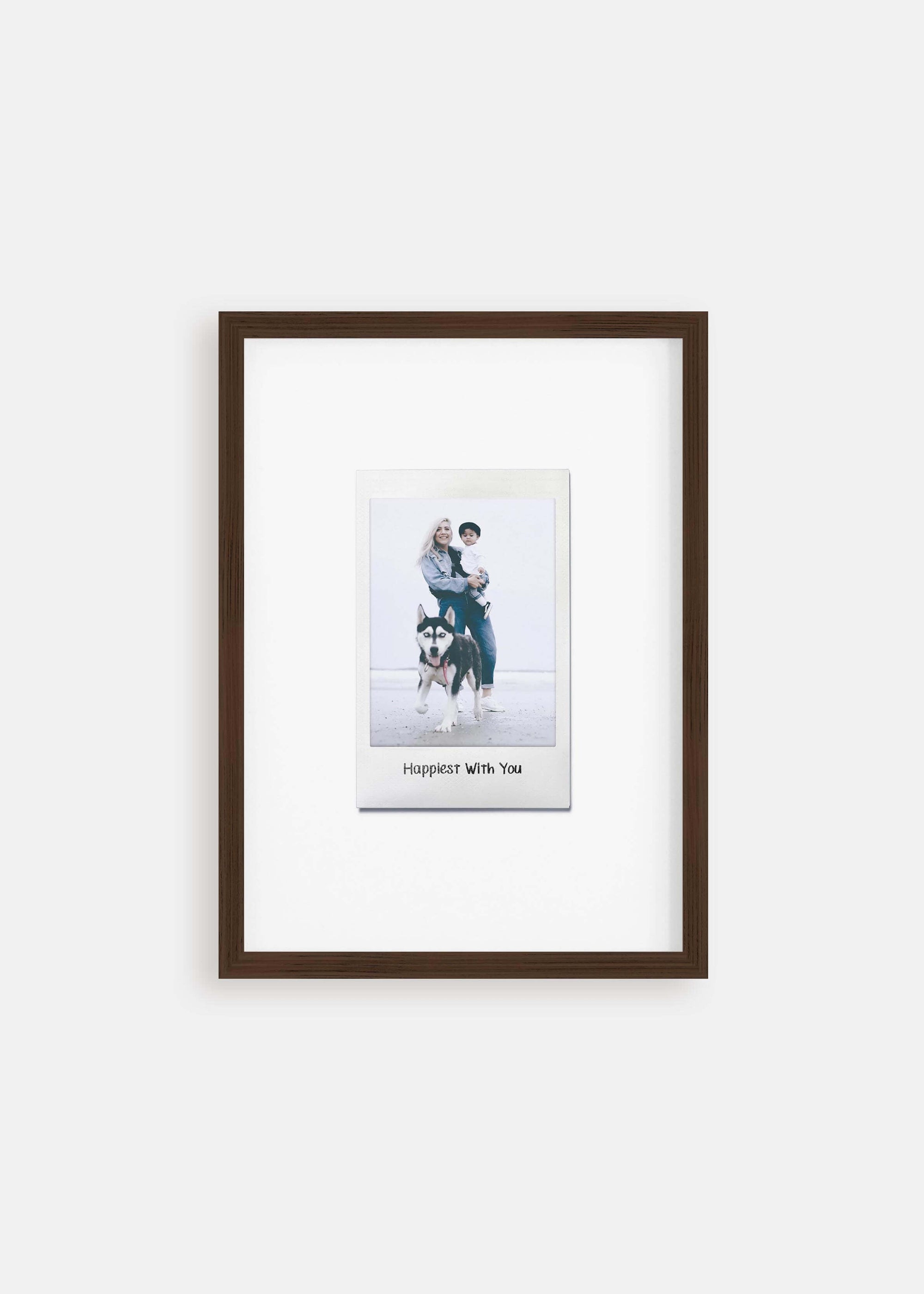 Personalized photo gift of a woman with her child and dog in a walnut frame in the style of a nostalgic instant film custom polaroid photo with frame on white background. The custom caption reads "Happiest with you".