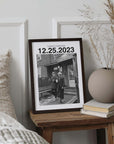 Personalized black and white photo gift with custom date in black frame on bedside table.