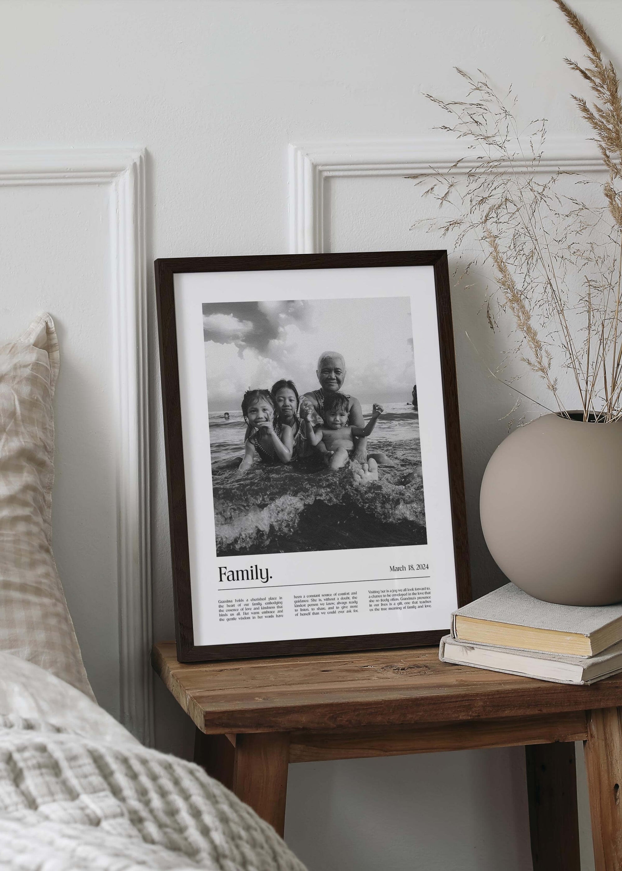 Personalized black and white photo gift of children with grandma and a custom message added. Black picture frame on small bedside table.